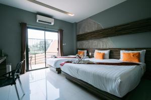 two beds in a room with a large window at Ray Hotel Buriram in Buriram