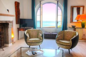 a living room with two chairs and a fireplace at Les Remparts Antibes Location in Antibes