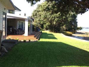 dom z ogródkiem z zieloną trawą w obiekcie Absolute Waterfront Serenity Near Auckland w mieście Clarks Beach