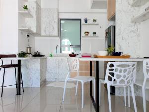 a white kitchen with white chairs and a table at Ipoh Meru Casa Kayangan by BeeStay in Ipoh