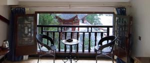 balcón con mesa, 2 sillas y ventana en Fenghuang Tujia Ethnic Minority River View Hotel, en Fenghuang