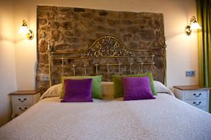 a bedroom with a large bed with purple and green pillows at Casa Rural Madre Pepa in Carreña de Cabrales