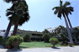 a building with palm trees in front of it at Hotel Yatrik in Allahābād
