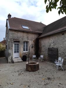 a stone house with two white chairs in front of it at AU VIEUX PUIT in Polisy