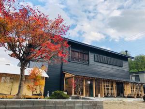 un edificio negro con un árbol delante de él en yuzaka - natural & sustainable inn - en Kazuno