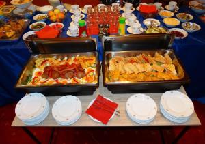 two trays of food on a table with plates at Budai Panzió in Székesfehérvár