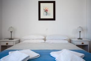 a white bedroom with a bed with towels on it at Paros Philoxenia in Chrissi Akti