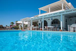 een zwembad met stoelen en tafels en een gebouw bij Paros Philoxenia in Chrissi Akti