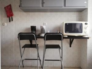 2 Stühle am Tisch mit Mikrowelle in der Unterkunft TripGeo Apartment Roma in Lissabon