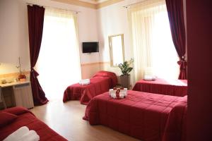 um quarto de hotel com três camas vermelhas e janelas em B&B The Queens em Foggia