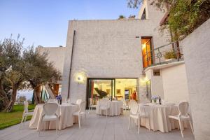 eine Terrasse mit weißen Tischen und Stühlen und ein Gebäude in der Unterkunft AMORE RENTALS - Villa Elia in Massa Lubrense