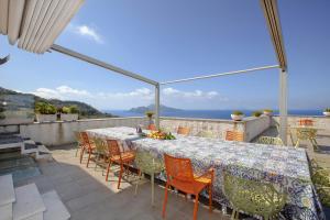 una mesa y sillas en un balcón con vistas al océano en AMORE RENTALS - Villa Elia en Massa Lubrense