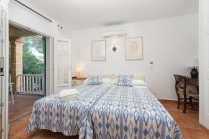 a bedroom with a bed with a blue and white comforter at Villa Herdain in Alcudia