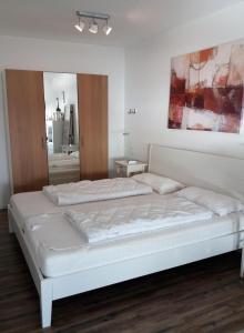 - une chambre blanche avec un grand lit blanc et un miroir dans l'établissement Vier Jahreszeiten Haus 2 Whg 46, à Großenbrode