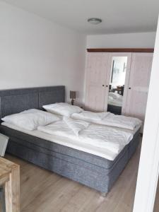 ein Schlafzimmer mit einem großen Bett mit weißer Bettwäsche in der Unterkunft Vier Jahreszeiten Haus 2 Whg 73 in Großenbrode