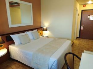 una habitación de hotel con una gran cama blanca y un espejo en RHI Porta Bologna, en Pieve di Cento