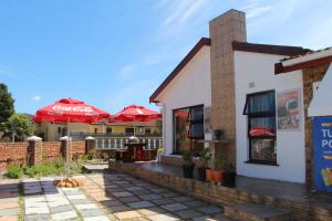 a restaurant with red umbrellas and a dog laying outside at Turning Point Bed & Breakfast in Cape Town
