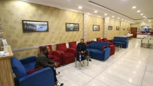 two men sitting in a waiting room with red chairs at Fly Hotel in Istanbul
