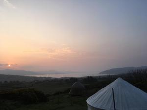 a tent in a field with the sunset in the background at Portsalon Luxury Camping in Portsalon