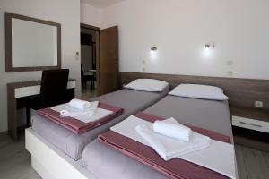 a bedroom with two beds with towels and a desk at Resort Trcol in Novalja