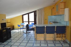 a room with a kitchen with blue chairs and a table at Mansarda Fronte Mare con servizio spiaggia incluso a Roseto degli Abruzzi in Roseto degli Abruzzi