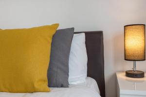 a bed with a yellow pillow and a lamp at River Rooms Nottingham in Nottingham