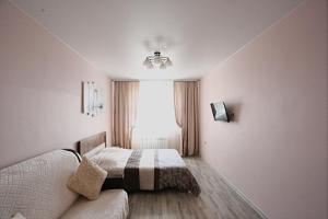 イルクーツクにあるАпартаменты на Байкальскойのベッドルーム1室(ベッド1台、ソファ、窓付)