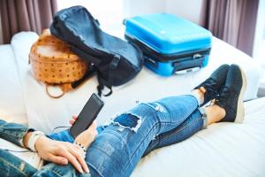 a woman laying on a couch with a cell phone and luggage at ibis budget Singapore Imperial in Singapore