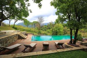 a swimming pool with chairs and a table next to at Sennya Resorts in Belihuloya