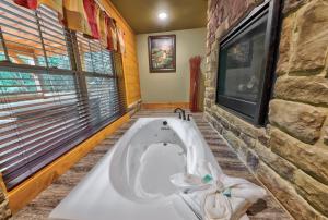 a bath tub in a bathroom with a stone wall at A Breath of Fresh Air chalet in Gatlinburg