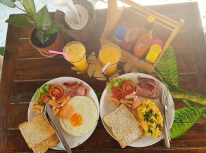 zwei Teller mit Frühstücksspeisen auf einem Holztisch in der Unterkunft Phuree Hut in Ko Phayam