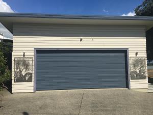 a garage door with two windows on a house at Absolute Waterfront Serenity Near Auckland in Clarks Beach