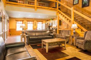 a living room with leather furniture and a staircase at A Hilltop Hideaway chalet in Gatlinburg