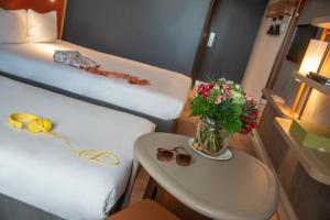a room with a bed and a table with a vase of flowers at ibis budget Nice Californie Lenval in Nice