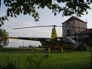 Chambres Rozies Dunes في ديونْ: طائرة هليكوبتر صفراء و زرقاء متوقفة في الميدان