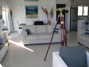 a living room with a white couch and a telescope at Trident Beach Apartment in Protaras