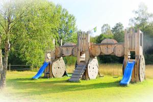 a wooden playground with a slide and swings at Vindängs Gård Hagbards By in Slöinge