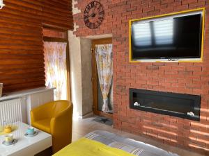 uma sala de estar com uma parede de tijolos e uma televisão de ecrã plano em Klinkierowy Apartament z wanną dla Dwojga em Gniezno