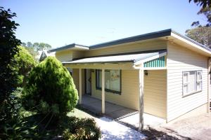 Una casa amarilla con un árbol delante. en Mayview, en Katoomba