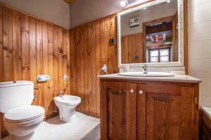 baño con paredes de madera, aseo y lavamanos en BARN THE RETREAT Acogedor apartamento en Arties, en Arties