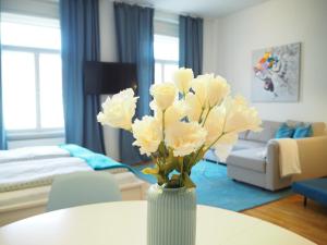 um vaso branco com flores brancas sobre uma mesa em City Residence Apartments FREE Parking & Self Check-in em Graz