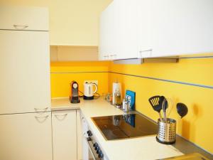 a small kitchen with yellow walls and white cabinets at APSTAY City Residence Apartments ǀ Parking option & Self Check-in in Graz