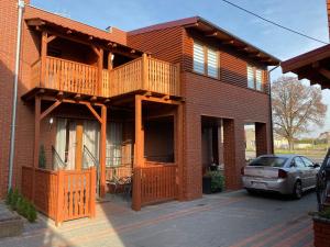 een huis met een balkon en een auto voor de deur bij Klinkierowy Apartament z wanną dla Dwojga in Gniezno