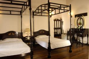 two canopy beds in a room with a mirror at Lake Palace in Thekkady
