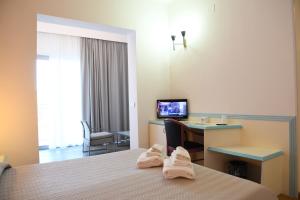a hotel room with a bed and a desk and a television at Orrì Hotel in Tortolì
