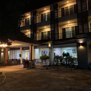 um prédio à noite com pessoas andando na frente dele em JB Mansion Hotel em Chiang Rai
