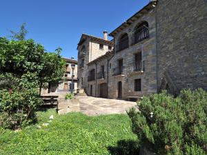 un grande edificio in mattoni con un prato davanti di Casa Coronas a El Pueyo de Araguás
