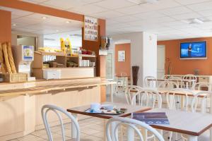 a fast food restaurant with tables and chairs at Premiere Classe Le Blanc Mesnil in Le Blanc-Mesnil
