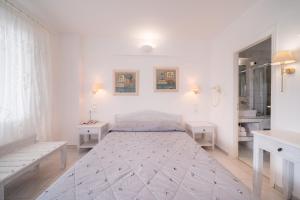 a white bedroom with a bed and two tables at Vardia Bay Studios in Karavostasi
