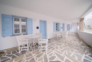 a room with white chairs and a table on a mosaic floor at Vardia Bay Studios in Karavostasi